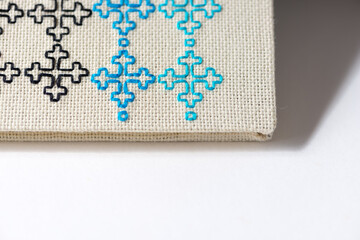 Obraz premium simple embroidery with black, blue, and cyan thread on off-white even-weave cloth, on a white background
