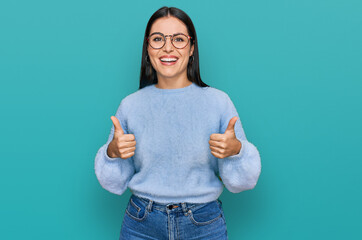 Young hispanic woman wearing casual clothes and glasses success sign doing positive gesture with...