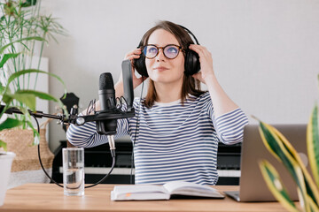 the stylish and educated caucasian woman records podcasts in a recording studio or in her home. the...