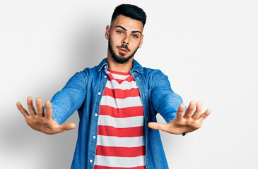 Young hispanic man with beard wearing casual denim jacket doing stop gesture with hands palms, angry and frustration expression