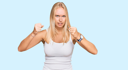 Fototapeta na wymiar Young blonde girl wearing casual style with sleeveless shirt angry and mad raising fists frustrated and furious while shouting with anger. rage and aggressive concept.
