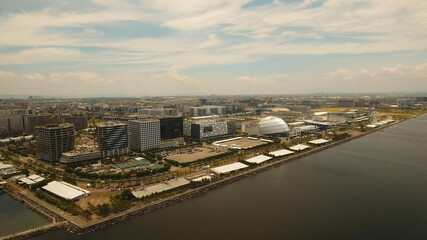 Fototapeta premium Aerial view of Manila city. Fly over city with skyscrapers and buildings n Mall of Asia. Aerial skyline of Manila. Modern city by sea, highway, cars, skyscrapers, shopping malls. Makati district