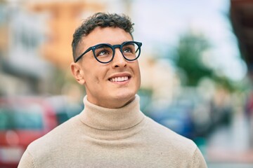 Young hispanic man smiling happy wearing glasses at the city.