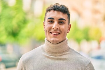 Young hispanic man smiling happy standing at the city.