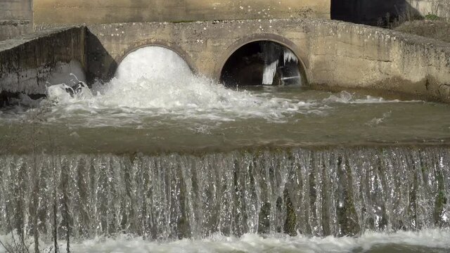 A dike or drainage dam, rapid water flowing from the pipes after heavy storm