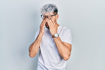 Young hispanic man with modern dyed hair wearing white t shirt and glasses rubbing eyes for fatigue and headache, sleepy and tired expression. vision problem