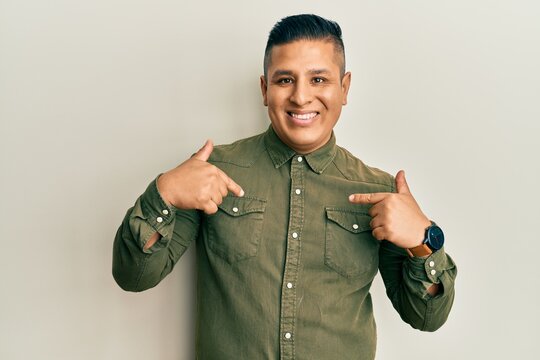 Young latin man wearing casual clothes looking confident with smile on face, pointing oneself with fingers proud and happy.