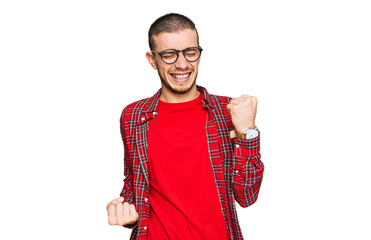 Hispanic young man wearing casual clothes celebrating surprised and amazed for success with arms...