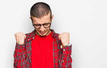 Hispanic young man wearing casual clothes excited for success with arms raised and eyes closed...