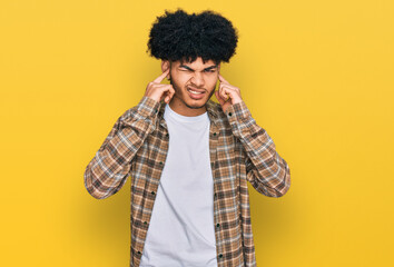Fototapeta na wymiar Young african american man with afro hair wearing casual clothes covering ears with fingers with annoyed expression for the noise of loud music. deaf concept.