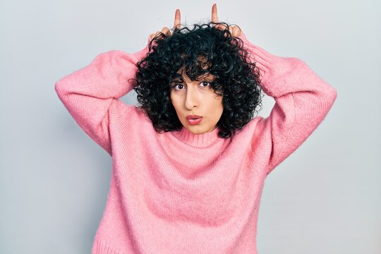 Young Middle East Woman Wearing Casual Clothes Doing Funny Gesture With Finger Over Head As Bull Horns