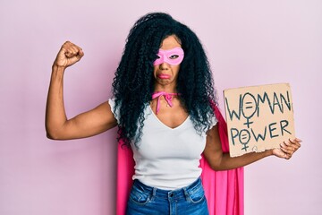 Middle age african american woman wearing super hero costume holding woman power banner depressed and worry for distress, crying angry and afraid. sad expression.