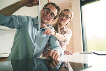 Young happy couple working from home showing chart on the video conference