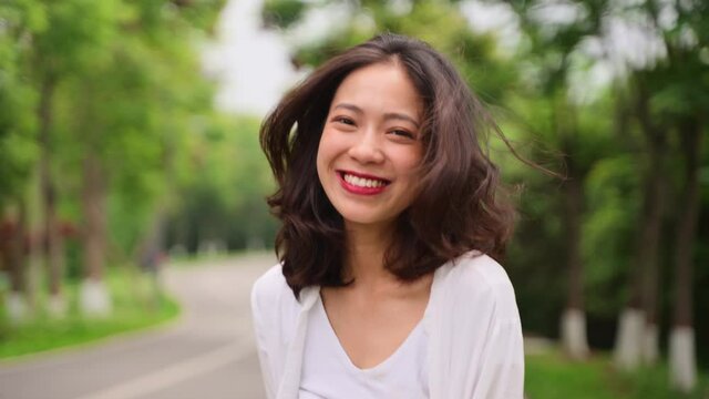 portrait of happy young asian woman looking at camera smile in the nature park
