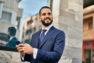 Young businessman smiling happy using smartphone at the city.