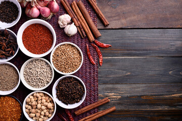 Various dry spices and herbs in a bowl on wooden background. Asian food ingredients (chili, clove, caraway, coriander seed, star anise, cardamom, pepper, cinnamon, garlic and shallot)