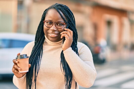 Young african american woman talking on the smartphone and drinking take away coffee at the city