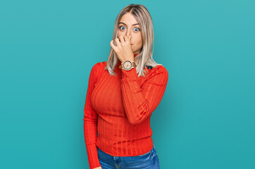 Beautiful blonde woman wearing casual clothes smelling something stinky and disgusting, intolerable...
