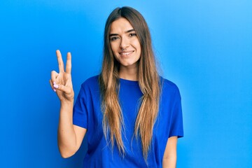 Fototapeta premium Young hispanic woman wearing casual clothes showing and pointing up with fingers number two while smiling confident and happy.