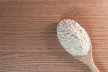 Wooden spoon with wheat flour on wooden table