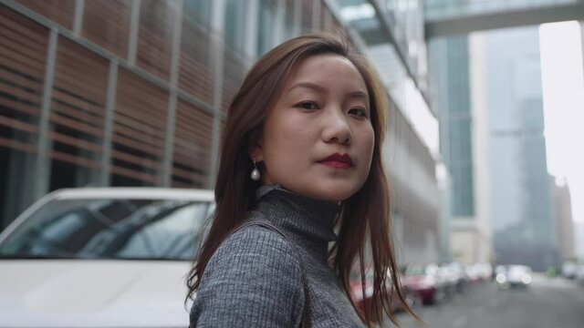 4k slow motion serious Asian woman looking at camera portrait in the urban street