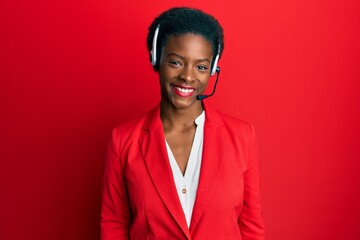 Young african american girl wearing call center agent headset looking positive and happy standing...