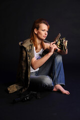 blonde woman in camouflage with arms on a dark background with studio