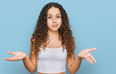 Teenager hispanic girl wearing casual clothes clueless and confused expression with arms and hands...