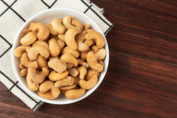 Top view of cashew nuts in white bowl on the table, Flat lay, Healthy snack, Vegetarian food.