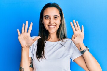Young hispanic woman wearing casual white t shirt showing and pointing up with fingers number nine...