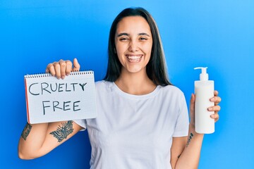 Young hispanic woman holding cruelty free cosmetics smiling and laughing hard out loud because...