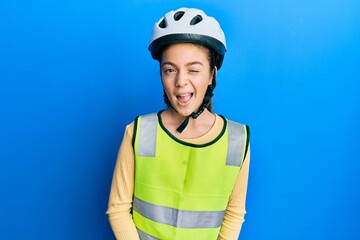 Beautiful brunette little girl wearing bike helmet and reflective vest winking looking at the camera with sexy expression, cheerful and happy face.