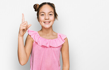 Beautiful brunette little girl wearing summer pink shirt pointing finger up with successful idea. exited and happy. number one.