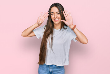 Young hispanic girl wearing casual white t shirt showing and pointing up with fingers number nine...