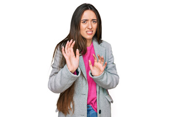 Young hispanic girl wearing business clothes disgusted expression, displeased and fearful doing disgust face because aversion reaction. with hands raised