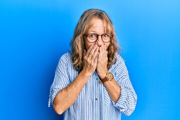 Middle age blonde woman wearing casual clothes and glasses laughing and embarrassed giggle covering...