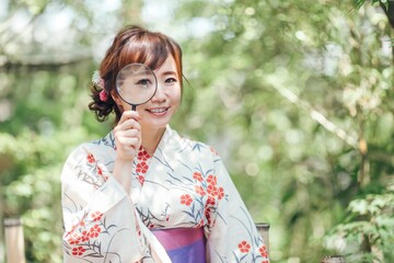 虫眼鏡を使う浴衣姿の女性
