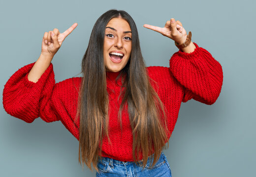 Beautiful hispanic woman wearing casual clothes smiling amazed and surprised and pointing up with fingers and raised arms.