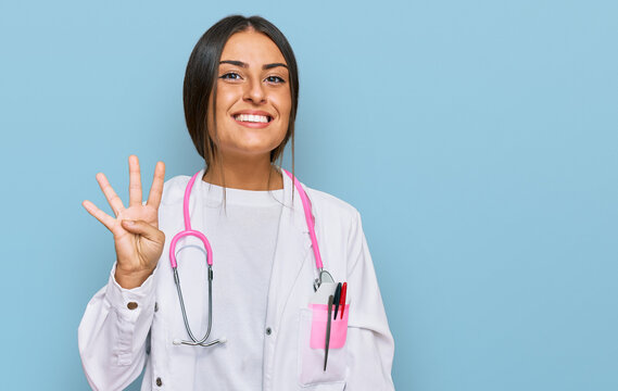Beautiful hispanic woman wearing doctor uniform and stethoscope showing and pointing up with fingers number four while smiling confident and happy.
