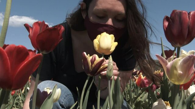 Woman In Fask Mask Smelling Flowers