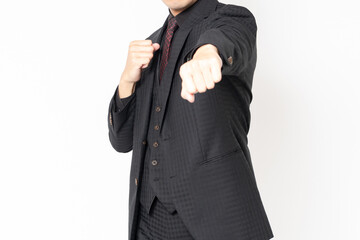 白背景の前に立って、パンチのジェスチャーをする男性ビジネスマン