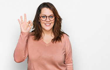 Young plus size woman wearing casual clothes and glasses smiling positive doing ok sign with hand and fingers. successful expression.