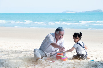 Grandfather and little granddaughter having fun on summer vacation on the beach seaside...