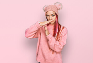 Young caucasian woman wearing casual clothes and wool cap doing time out gesture with hands,...