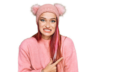 Young caucasian woman wearing casual clothes and wool cap pointing aside worried and nervous with...