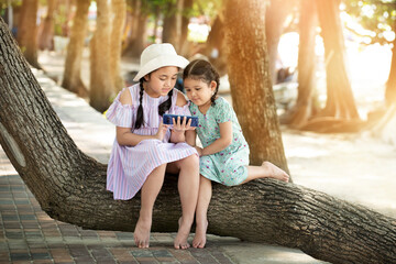 Obraz premium Cute two little kids girl using smartphone playing game in park