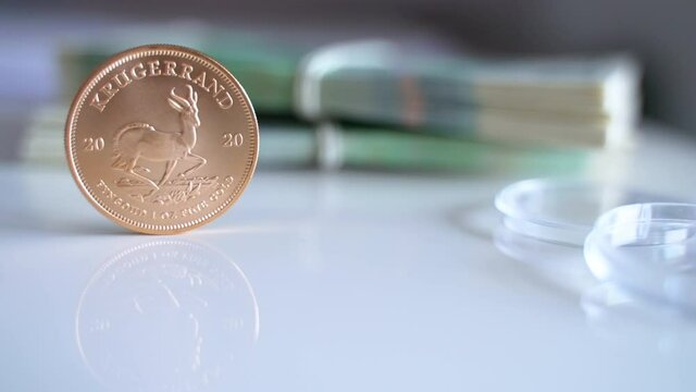 High-quality footage of the South African Krugerrand Coin in a vertical position and the Official currency of Poland in the background. Two sets of Polish zloty and Krugerrand. Narodowy Bank Polski. 