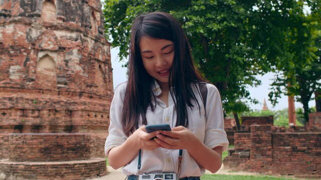 Cheerful beautiful young Asian backpacker blogger woman casual with camera look at photo on smartphone smile with happy face travel pagoda at the old city, Lifestyle tourist travel holiday concept.