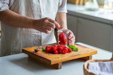 Man taking raspberries from jar at kitchen.
