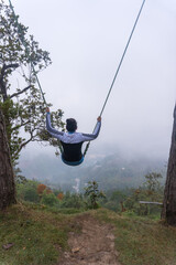 a Hispanic woman on a long swing with a view of the forest in Tekilatlakpan, Mexico